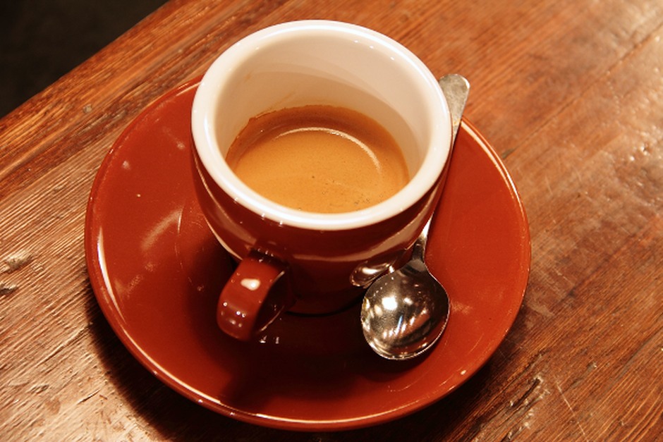A cup of coffee on a wooden table, photographed in warm natural tones.